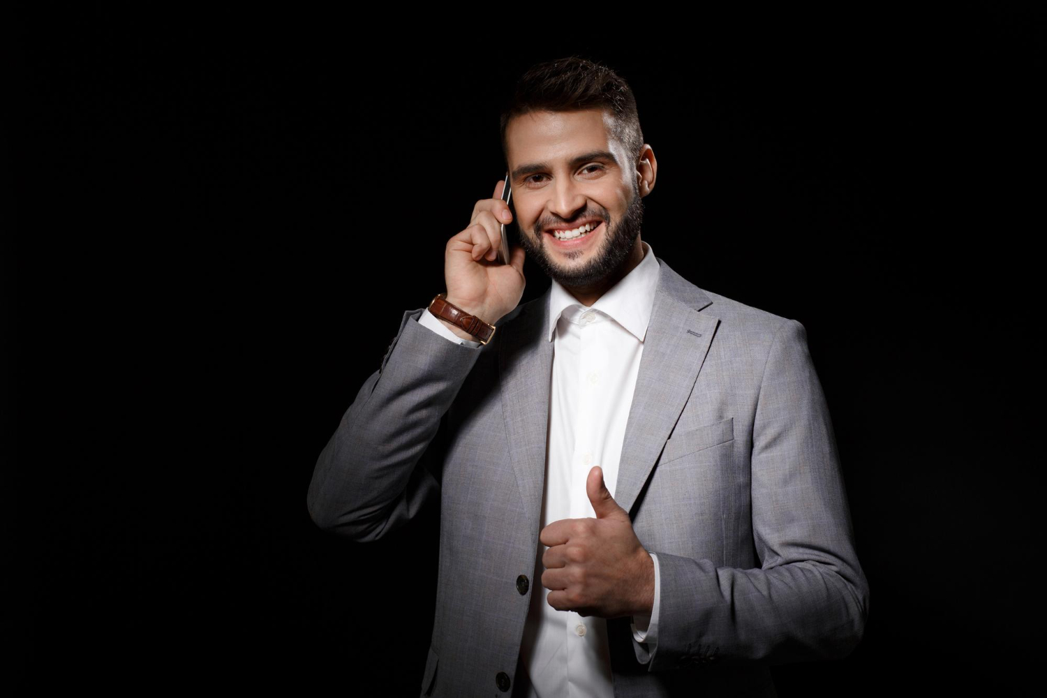 Homme en costume au téléphone avec pouce levé.